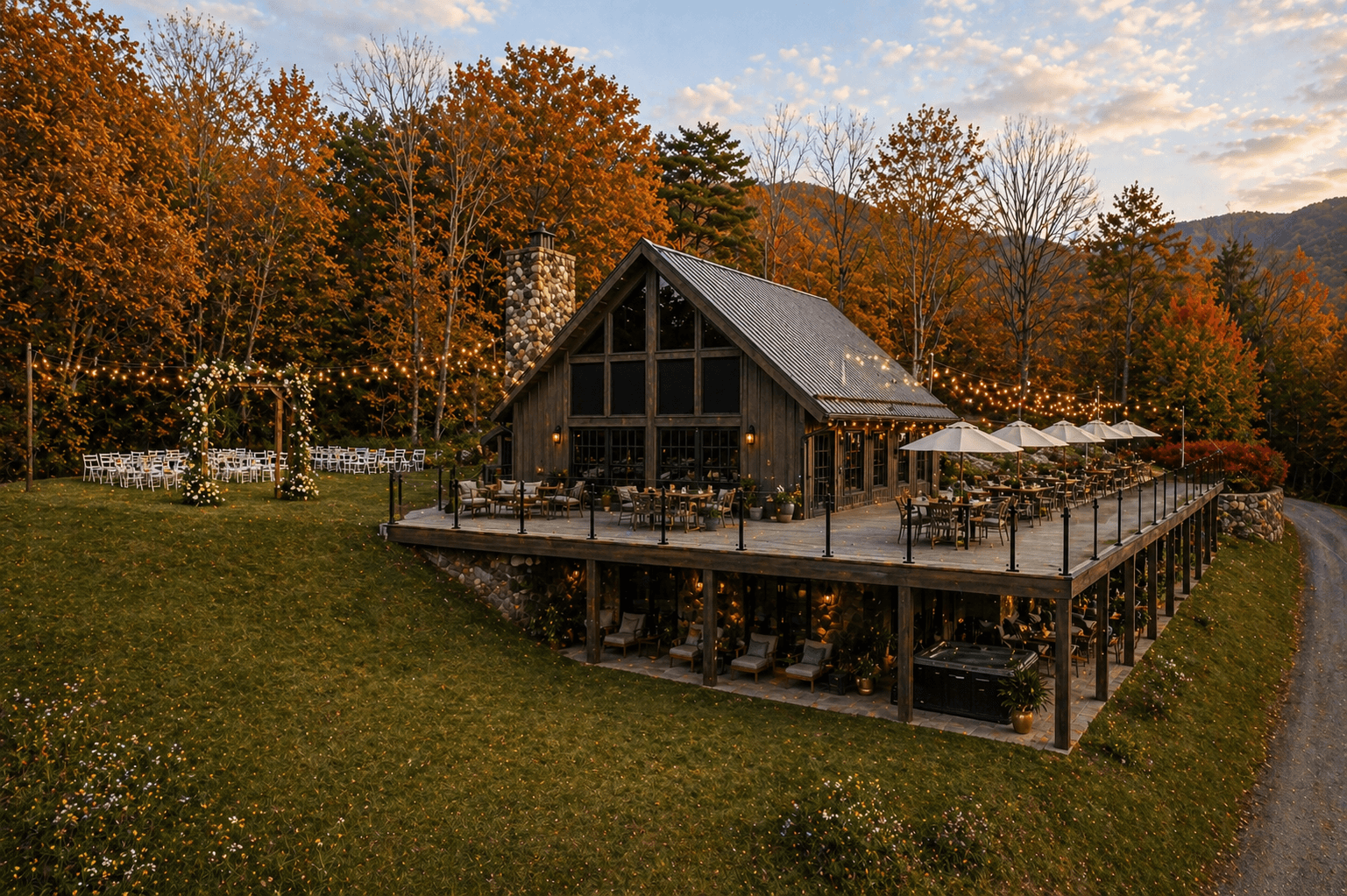 A rustic lodge surrounded by colorful autumn trees, featuring an outdoor deck with dining areas and string lights.